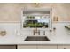 Close-up of kitchen sink with stainless steel faucet, white countertops, and window view at 1905 Pine Tree Ln, Belleair Bluffs, FL 33770