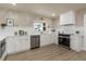 Bright white kitchen with stainless appliances, white countertops, gold hardware, and woodgrain flooring at 1905 Pine Tree Ln, Belleair Bluffs, FL 33770