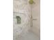Walk-in shower featuring neutral accent tiles, a gold shower head, body wand, decorative plant, and niche at 1905 Pine Tree Ln, Belleair Bluffs, FL 33770