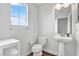 Bright bathroom with a pedestal sink, modern toilet, and a view from the bright window at 21028 Ski Way, Land O Lakes, FL 34638