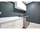 Laundry room showcases stainless steel washer and dryer, white cabinetry, and dark wall paint at 21028 Ski Way, Land O Lakes, FL 34638