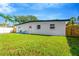 The backyard has lush green grass and a charming white building, with a sturdy wooden fence at 219 80Th Ne Ave, St Petersburg, FL 33702