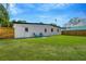 Manicured backyard with healthy green lawn, a charming white building, and a sturdy wooden fence at 219 80Th Ne Ave, St Petersburg, FL 33702