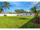 Expansive backyard featuring lush green grass, a white fence, and tropical palm trees, perfect for outdoor activities at 219 80Th Ne Ave, St Petersburg, FL 33702
