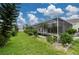 Spacious backyard featuring a screened-in pool area, lush lawn, and manicured garden beds at 23420 Peachland Blvd, Port Charlotte, FL 33954