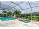 Inviting screened-in pool and spa area with travertine deck and lush landscaping at 23420 Peachland Blvd, Port Charlotte, FL 33954