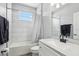 Bathroom with white tiled walls, a window, a sink with a black faucet and a shower and tub with a white shower curtain at 3046 Donington Castle Ln, Land O Lakes, FL 34638