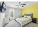 Bright bedroom with a yellow accent wall, window with natural light, and a ceiling fan creating a comfortable space at 3046 Donington Castle Ln, Land O Lakes, FL 34638