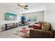 Bright living room featuring a large sectional sofa, a ceiling fan and a wall-mounted TV above a modern wooden table at 3046 Donington Castle Ln, Land O Lakes, FL 34638