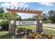 A decorative community sign with brick columns, flowers, and greenery welcomes residents and visitors at 3046 Donington Castle Ln, Land O Lakes, FL 34638