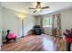 Bright bedroom featuring wood floors, ceiling fan, and a comfortable recliner with natural light from the window at 3932 Watson Dr, New Port Richey, FL 34655