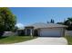 Inviting single-story residence featuring a two-car garage, manicured lawn, and a blue front door at 404 Oakmount Rd, Clearwater, FL 33765