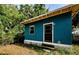 Cozy blue home featuring a cute window and functional entry door with wooden steps at 41 W Boyer St, Tarpon Springs, FL 34689