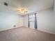 Spacious bedroom featuring neutral carpet, a ceiling fan, and a window with blue curtains at 44 Pinewood Cir, Safety Harbor, FL 34695