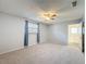 Spacious bedroom featuring a ceiling fan, neutral carpet, and a window with blue curtains at 44 Pinewood Cir, Safety Harbor, FL 34695