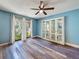 An empty living area with wood floors, a ceiling fan, and a large window view to the exterior at 44 Pinewood Cir, Safety Harbor, FL 34695