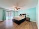 Bright main bedroom featuring wood floors, fan, sliding doors to the pool, and colorful decor at 44 Pinewood Cir, Safety Harbor, FL 34695
