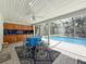 Outdoor dining area adjacent to a sparkling pool and screened enclosure at 44 Pinewood Cir, Safety Harbor, FL 34695
