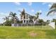 Luxury two-story home with a balcony, lush landscaping, and a white fence at 5405 Tybee Island Dr, Apollo Beach, FL 33572