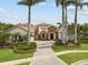 Stunning estate home featuring a terracotta tile roof, lush landscaping, and a brick driveway, surrounded by mature palm trees at 5405 Tybee Island Dr, Apollo Beach, FL 33572