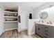 A lovely bathroom with gray cabinets, a white countertop, a walk-in shower, and storage shelves at 7404 Bay Dr, Tampa, FL 33635