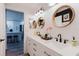 Bright bathroom with a double sink, white cabinets and striking, round mirrors next to the kitchen at 7404 Bay Dr, Tampa, FL 33635