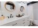 Bright bathroom with a double sink, white cabinets and striking, round mirrors at 7404 Bay Dr, Tampa, FL 33635