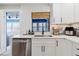 Cozy kitchen features stainless steel dishwasher, white cabinets, quartz countertops, and black hardware at 7404 Bay Dr, Tampa, FL 33635