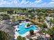 Aerial community shot of clubhouse and pool featuring sun loungers, playground, palm trees, and cabanas at 7699 Windchase Way, Wesley Chapel, FL 33545