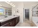 Bright bathroom with double sink vanity, glass-enclosed shower, and a walk-in closet for optimal storage at 7699 Windchase Way, Wesley Chapel, FL 33545
