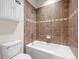 Cozy bathroom features a standard toilet, a tiled shower-tub combo with brown accent tiles, and wall storage at 7699 Windchase Way, Wesley Chapel, FL 33545