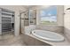Modern bathroom featuring a glass shower, a soaking tub, and a walk-in closet for convenient storage at 7699 Windchase Way, Wesley Chapel, FL 33545