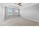 Spacious bedroom features neutral carpet, tray ceiling with fan, and ample natural light from two large windows at 7699 Windchase Way, Wesley Chapel, FL 33545