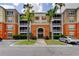 Exterior shot of condos with orange and beige siding, balconies, and manicured landscaping at 7901 Seminole Blvd # 1103, Seminole, FL 33772