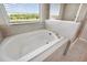 Close-up view of a soaking tub with tile surround and a window, offering a spa-like experience at 8595 Prairie Creek Dr, New Port Richey, FL 34655