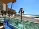 Balcony view of palm trees, a shuffleboard court, beach, and ocean at 880 Mandalay Ave # N109, Clearwater Beach, FL 33767