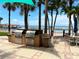 Outdoor grilling area with stainless steel appliances, patio dining, and palm trees with ocean backdrop at 880 Mandalay Ave # N109, Clearwater Beach, FL 33767