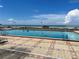 A clean, outdoor community pool surrounded by brick pavers, with the ocean just beyond the fence at 880 Mandalay Ave # N109, Clearwater Beach, FL 33767