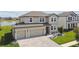 An aerial view of a two story home that features an attached three car garage and manicured lawn at 9287 Crescent Ray Dr, Wesley Chapel, FL 33545