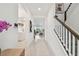 Hallway featuring staircase, white walls, light colored ceramic tile flooring, and open concept design at 9287 Crescent Ray Dr, Wesley Chapel, FL 33545