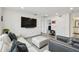 Open living room with hardwood floors, modern sofa, and large TV, perfect for entertaining at 9287 Crescent Ray Dr, Wesley Chapel, FL 33545