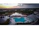 Aerial view of a unique pool with ample seating and recreational space beside a picturesque lake at sunset at 9516 Newdale Way # 101, Riverview, FL 33578