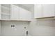 A well-lit laundry room with overhead cabinets and connections for a washer and dryer at 10420 Echo Dock Loop, San Antonio, FL 33576