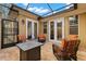 Enclosed lanai featuring wicker chairs, travertine tile, and outdoor lighting at 11308 Temperley Pl, Tampa, FL 33625
