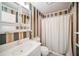 Traditional bathroom featuring a vanity, toilet, shower with curtain, and patterned wallpaper at 11514 Sun Rd, Dade City, FL 33525