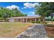 Charming brick ranch with mature landscaping and a long driveway leading to a two-car garage at 11514 Sun Rd, Dade City, FL 33525