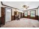 Living room featuring wainscotting, a ceiling fan, neutral paint and carpet, and a built-in bookcase at 11514 Sun Rd, Dade City, FL 33525