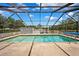 Outdoor pool inside screened enclosure with spacious patio area and pool accessories for maintenance at 11514 Sun Rd, Dade City, FL 33525