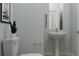 Well-lit bathroom featuring a pedestal sink, toilet, mirror, and modern fixtures at 11546 E 71St Ter, Palmetto, FL 34221