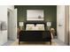Cozy bedroom with an olive green wall, complemented by a stylish black bed frame and beach-themed artwork at 11554 71St E Ave, Palmetto, FL 34221